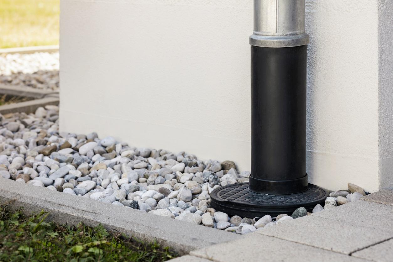 Downpipe into French Drain Stones Floor Around Wall Building